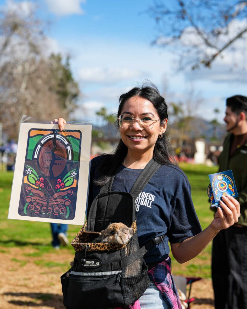 a girl holding up artwork and a bunny in a bag 
