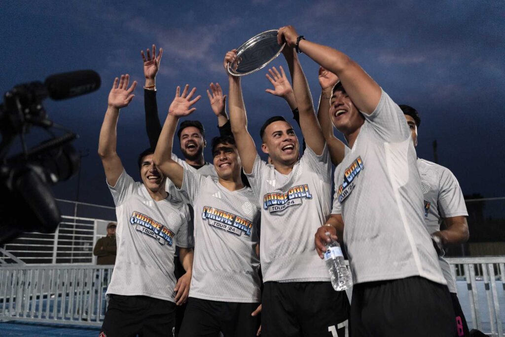 a group of men in white shirts holding a trophy in the air 